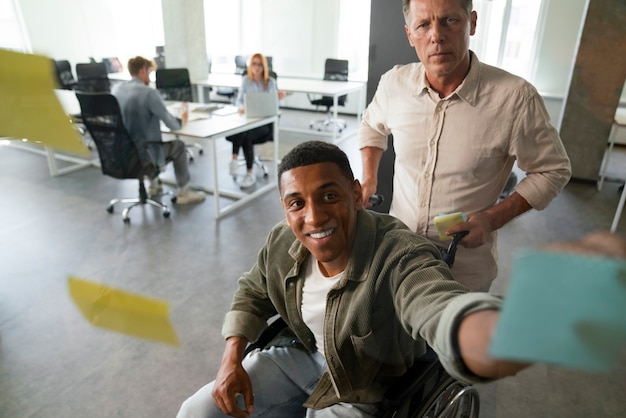 Foto gratuita uomo disabile su una sedia a rotelle che lavora nel suo lavoro d'ufficio