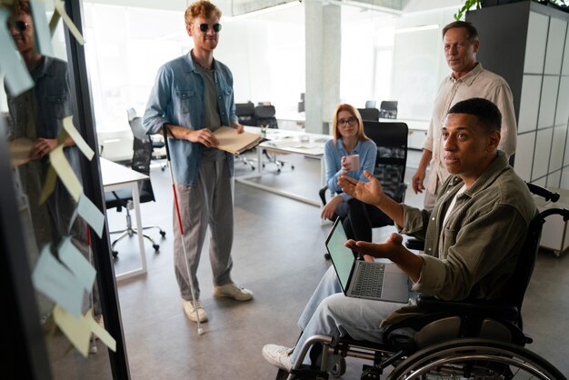 彼のオフィスの仕事で働いている車椅子の障害者の男性