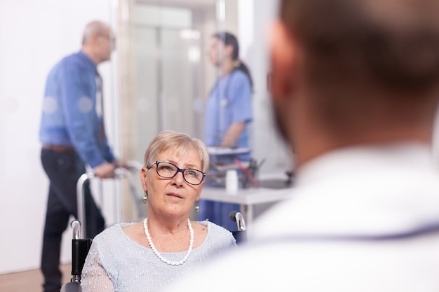 Disabled old person in wheelchair during treatment with geriatrician doctor