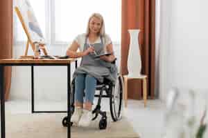 Foto gratuita persona disabile nella pittura su sedia a rotelle