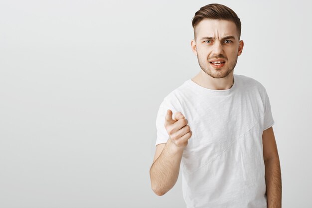 Disappointed and angry young man pointing finger in accusation, scolding someone