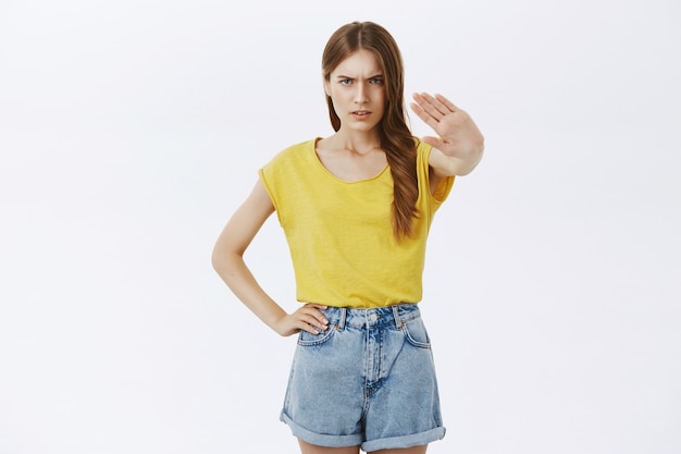 Disappointed frowning girl showing stop gesture, prohibit or refuse something omnious