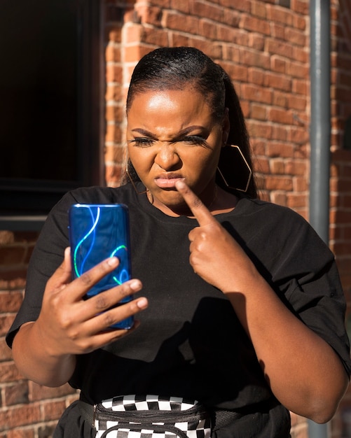 Foto gratuita ragazza delusa guardando il suo telefono