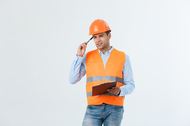 Разочарованный красивый инженер в оранжевом жилете и джинсах со шлемом, изолированным на белом фоне.