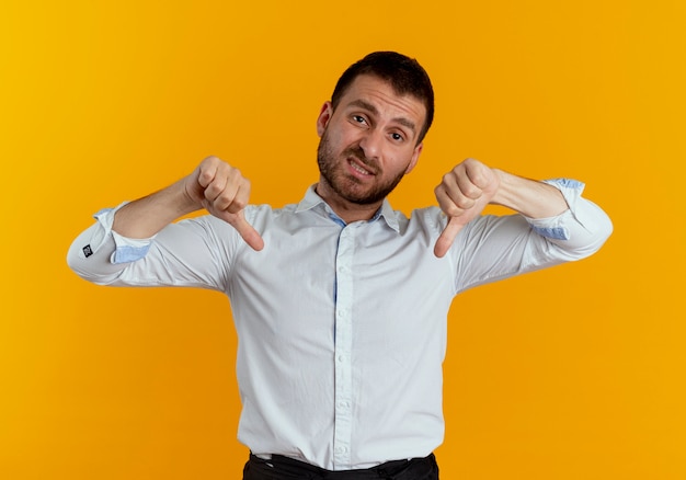 Disappointed handsome man thumbs down with two hands isolated on orange wall