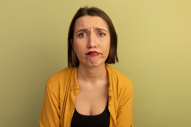 Disappointed pretty woman looks at front isolated on olive green wall