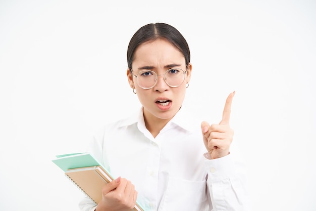 Free photo disappointed serious japanese teacher woman shakes finger in disapproval scolding student standing o