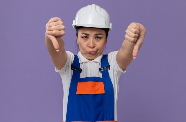 Бесплатное фото Разочарованная молодая азиатская девушка-строитель с белым защитным шлемом, листая вниз