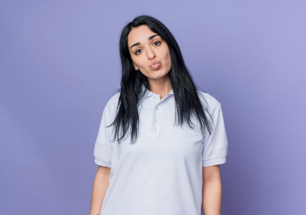 Disappointed young brunette caucasian girl looks isolated on purple wall