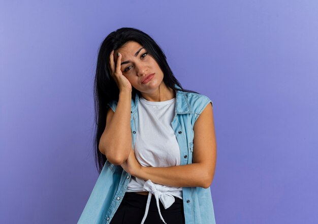 Disappointed young caucasian girl holds head looking at camera isolated on purple background with copy space