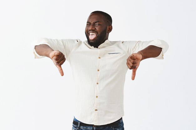 Disappointed young guy posing against the white wall