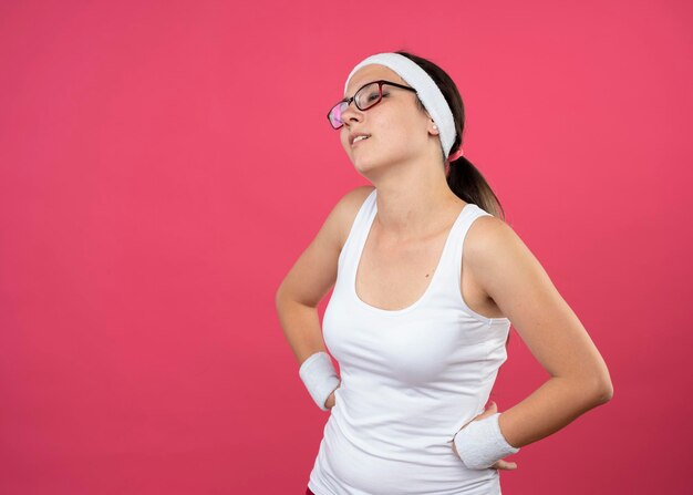 Disappointed young sporty girl in optical glasses wearing headband