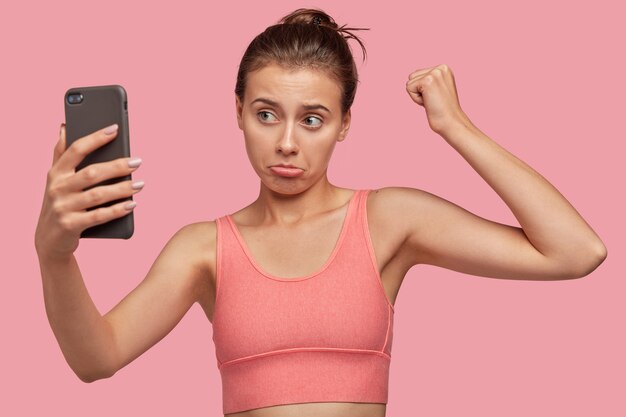 Discontent athletic woman posing against the pink wall