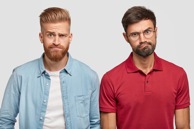 Бесплатное фото Недовольство бородатыми братьями позируют у белой стены