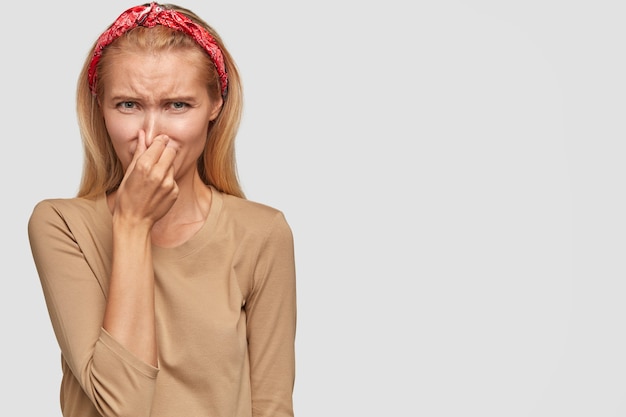 Free photo discontent blonde young woman posing against the white wall