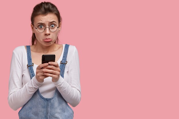 不満白人女性は唇を財布に入れ、後悔と不満を感じ、コミュニケーションのために最新のスマートフォンを使用します