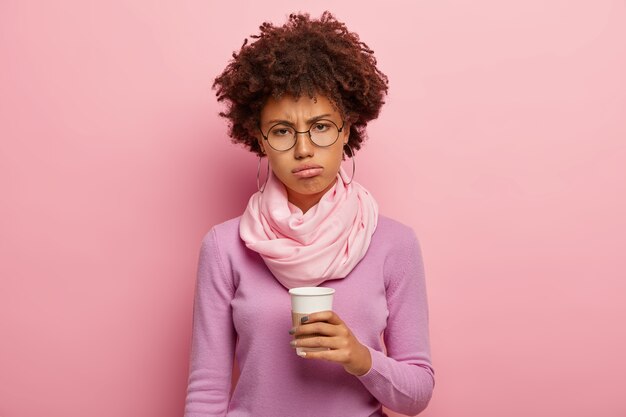 Discontent dark skinned woman has gloomy expression after awakening early in morning