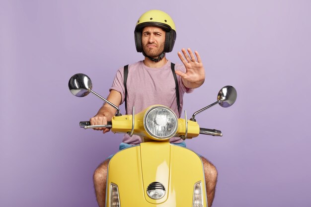 Discontent guy with helmet driving yellow scooter