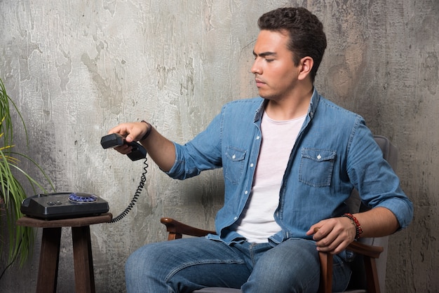 Free photo disgruntled man holding handset and sitting on chair. high quality photo