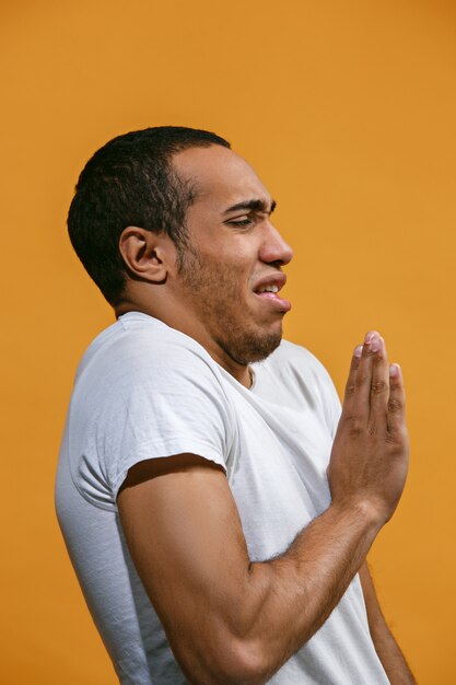 Disgust Afro-American man is looking disgustingly against orange space