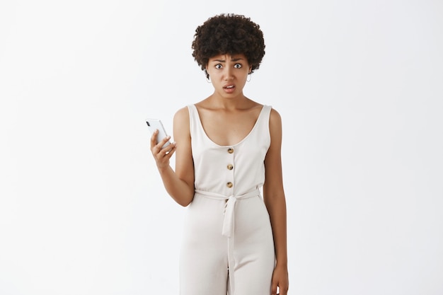 Disgusted stylish girl posing against the white wall