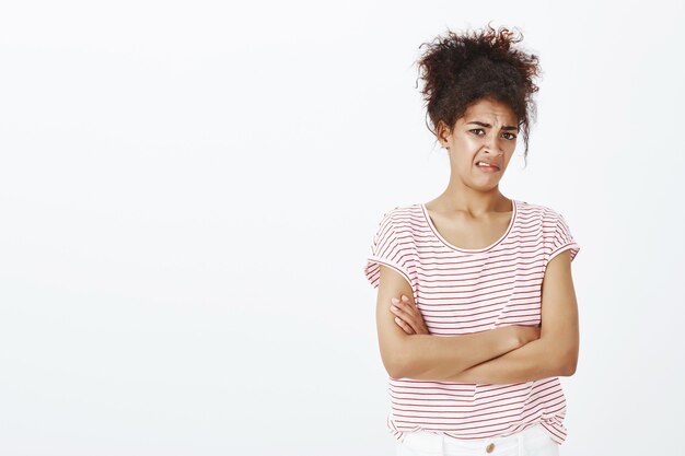 Disgusted unimpressed woman with afro hairstyle posing in the studio