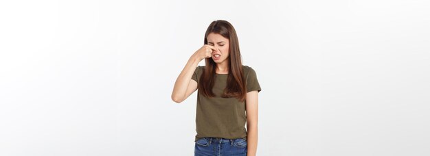 Disgusted young blonde closing her nose with her fingers isolated over white background