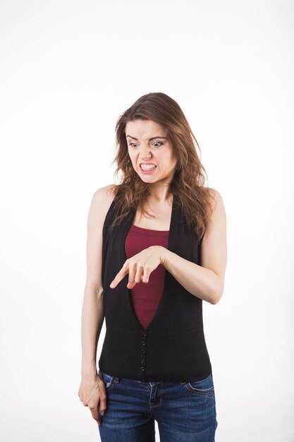 Disgusted young woman point down against white background