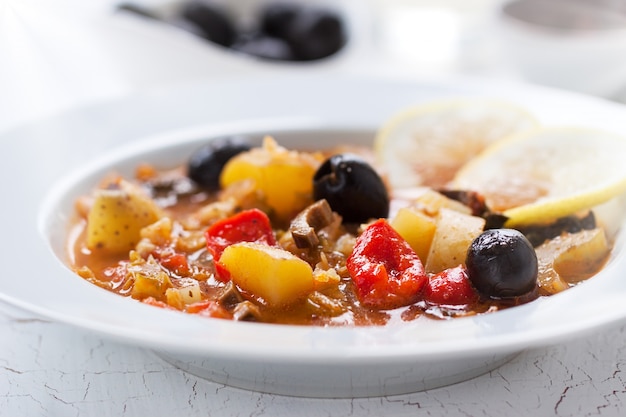 Dish of potatoes with black olives and tomatoes