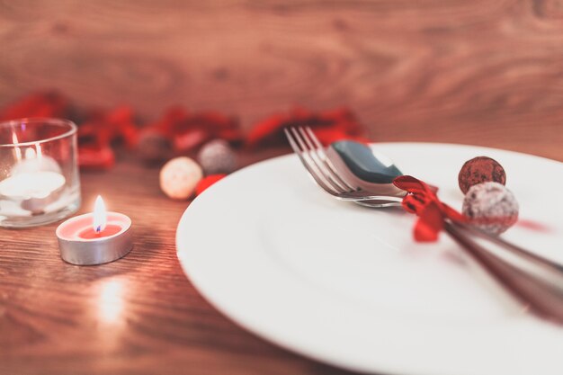 Dish with cutlery with a bow and a burning candle