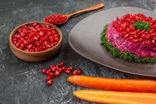 dish with herbs pomegranate seeds spoon carrots