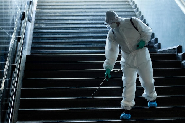 Дезинфектор опрыскивает лестницу метро из-за пандемии COVID-19