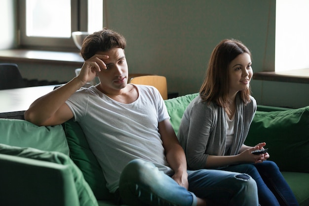 Disinterested boyfriend getting bored while excited girlfriend watching tv series