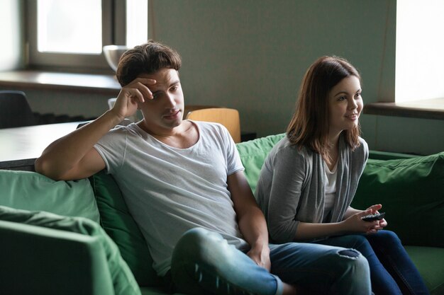 Disinterested boyfriend getting bored while excited girlfriend watching tv series