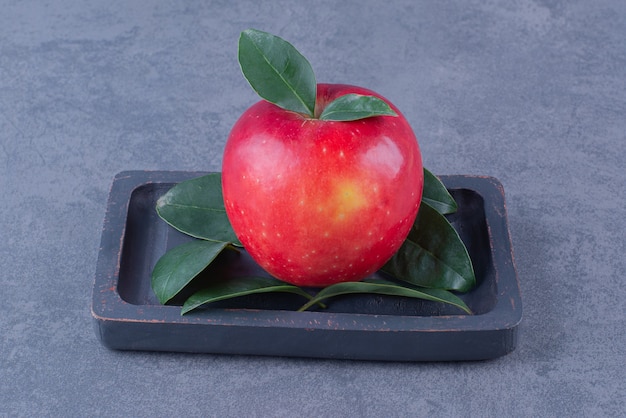 Free photo a display of apple on a wooden plate on marble table.