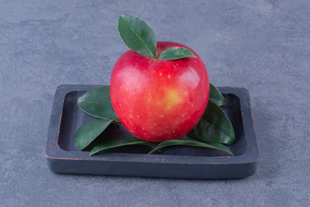 大理石のテーブルの上の木の板の上のリンゴの表示。