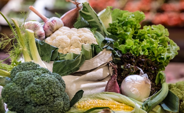 Display of fresh ripe organic broccoli, salad with greens and vegetables in cotton bag at the weekend farmer's market