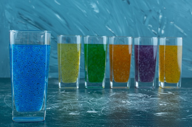 A display of juice glasses lined up on the blue background. High quality photo