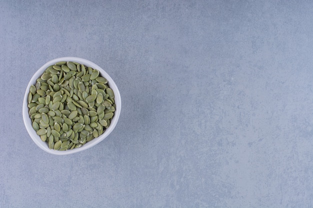 A display of pumpkin seeds in a bowl on marble.