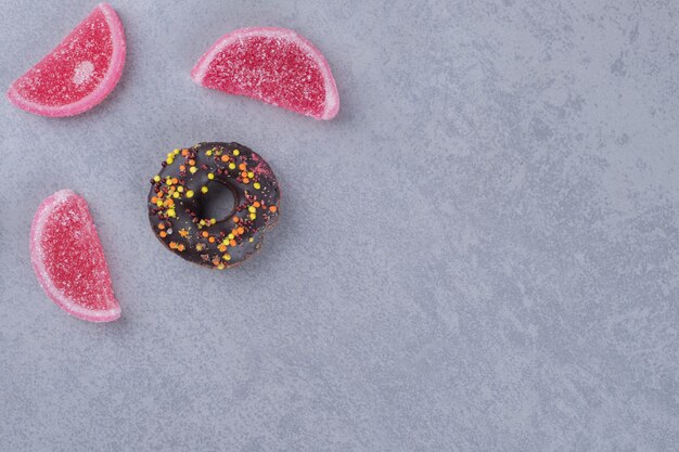 Display of a small donut and three marmelades on marble surface