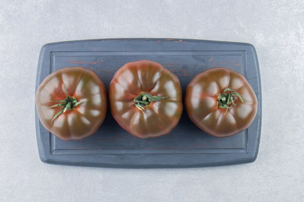 A display of tomatoes on the tray on the marble surface