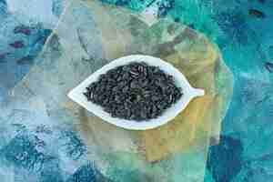 Free photo a display of unpeeled sunflower seeds on tulle , on the marble table.