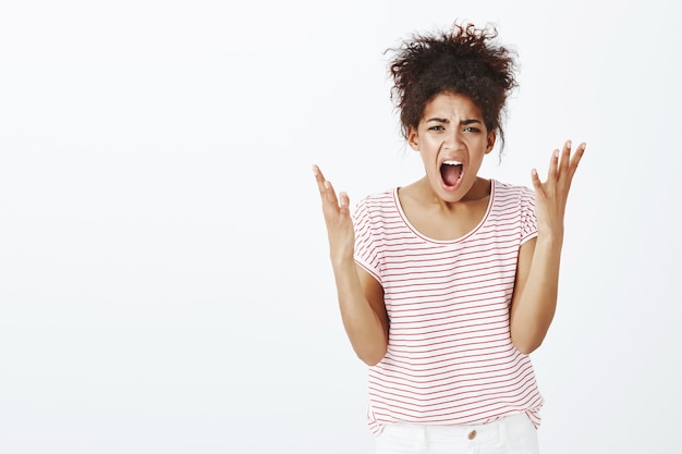 displeased angry woman with afro hairstyle posing in the studio