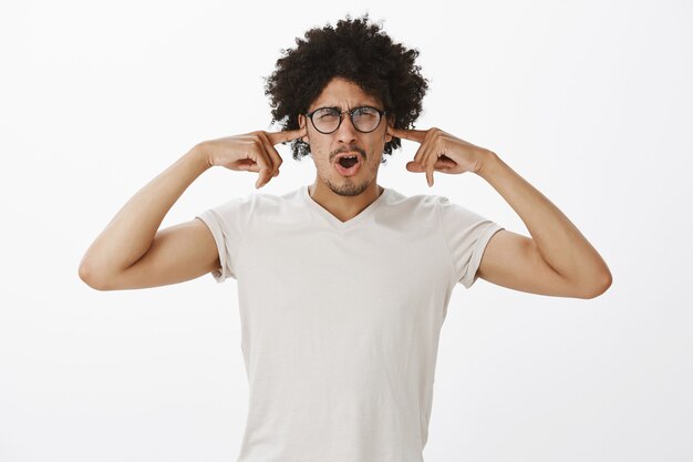 Displeased arguing man in glasses shut ears from awful noise