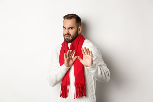 Displeased bearded man asking to stay away, showing decline and stop gesture, refrain from something bad, standing over white background