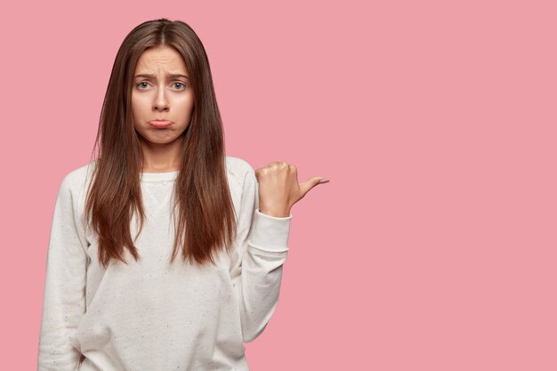 Displeased beautiful brunette posing against the pink wall