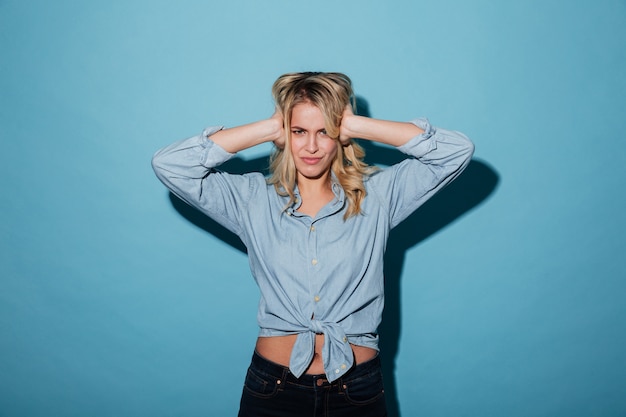 Free photo displeased blonde woman in shirt covering her ears