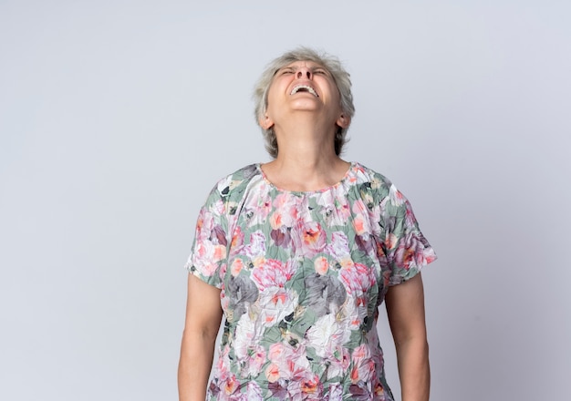 Displeased elderly woman looks up isolated on white wall