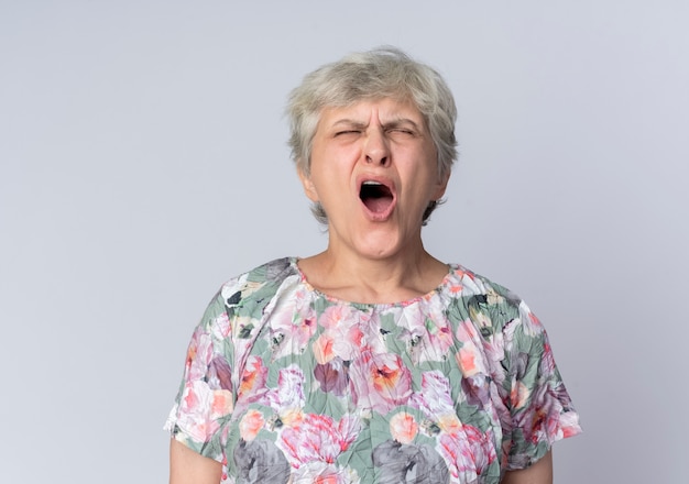 Недовольная пожилая женщина кричит с закрытыми глазами, изолированными на белой стене