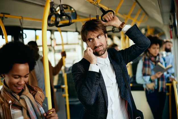 Displeased entrepreneur making a phone call while commuting to work by bus